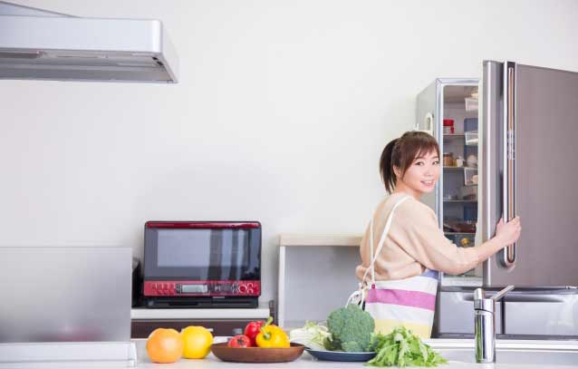 野菜を冷蔵庫から出す女性